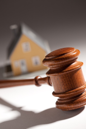 Wooden gavel with a model house in the background
